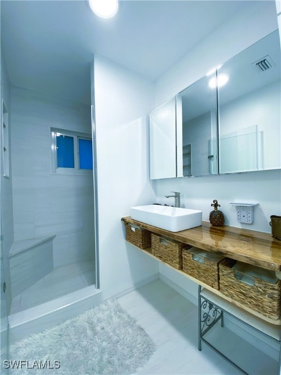 full bath featuring a sink, visible vents, and a shower stall