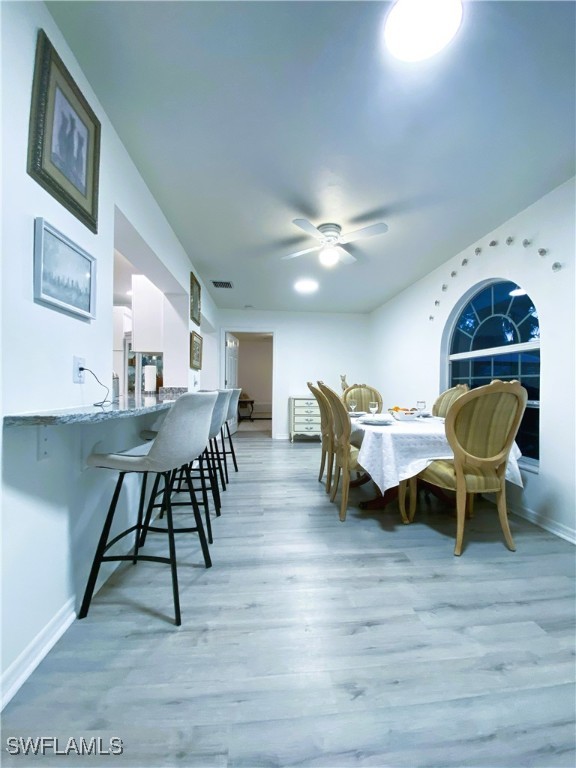 dining area featuring a ceiling fan, baseboards, and light wood-type flooring