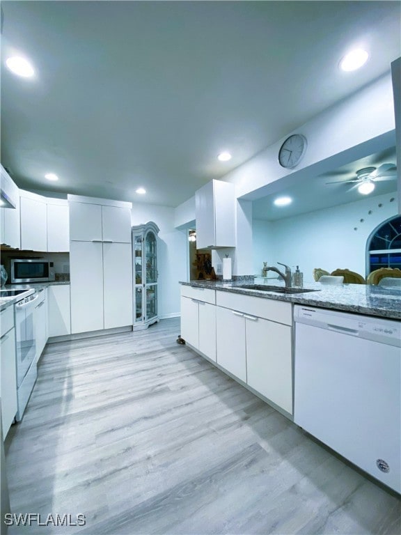 kitchen with white appliances, recessed lighting, a sink, white cabinets, and light wood-style floors