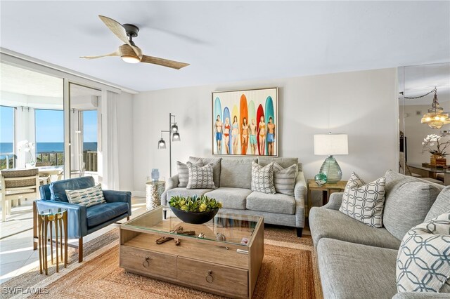 living room featuring ceiling fan with notable chandelier and a water view