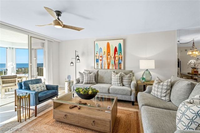 living room featuring a water view, a wall of windows, and ceiling fan with notable chandelier