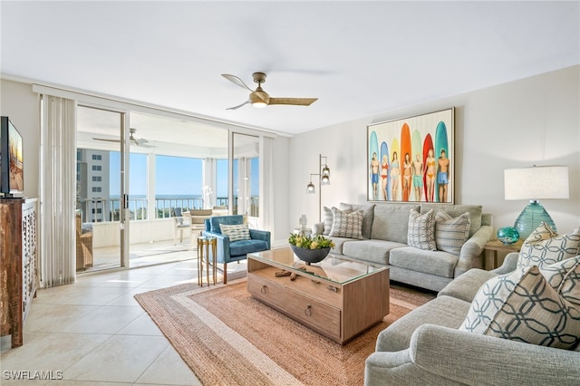 living room featuring light tile patterned floors, expansive windows, ceiling fan, and a water view