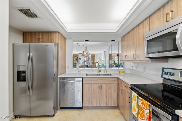 kitchen with decorative light fixtures, sink, a tray ceiling, stainless steel appliances, and light brown cabinets