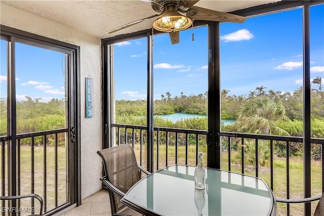 unfurnished sunroom featuring ceiling fan and a water view