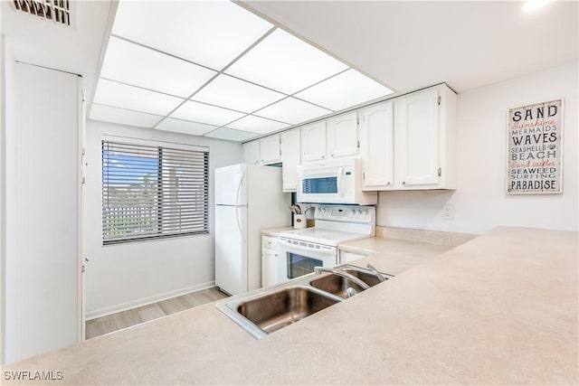 kitchen with white cabinetry, sink, white appliances, and light wood-type flooring