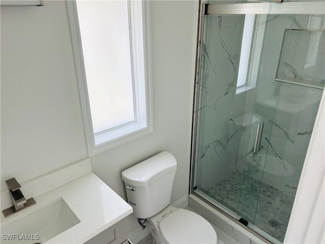 bathroom with walk in shower, vanity, and toilet