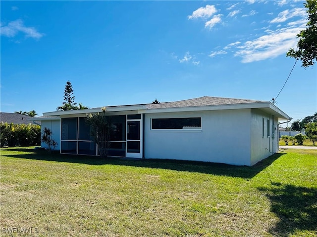 rear view of property featuring a sunroom and a lawn