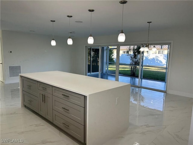 kitchen with gray cabinets, plenty of natural light, a kitchen island, and hanging light fixtures