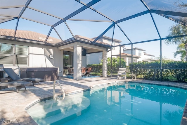 view of swimming pool featuring glass enclosure, a hot tub, and a patio area