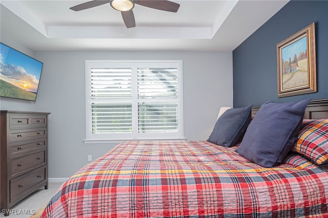 carpeted bedroom featuring a tray ceiling and ceiling fan