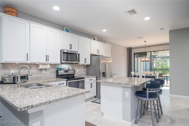 kitchen featuring sink, a kitchen island, tasteful backsplash, white cabinets, and appliances with stainless steel finishes