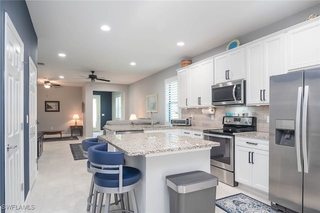 kitchen featuring backsplash, a kitchen bar, white cabinetry, and stainless steel appliances