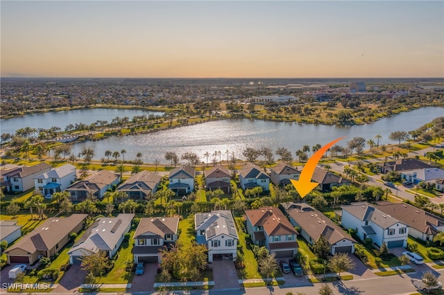 aerial view at dusk featuring a water view