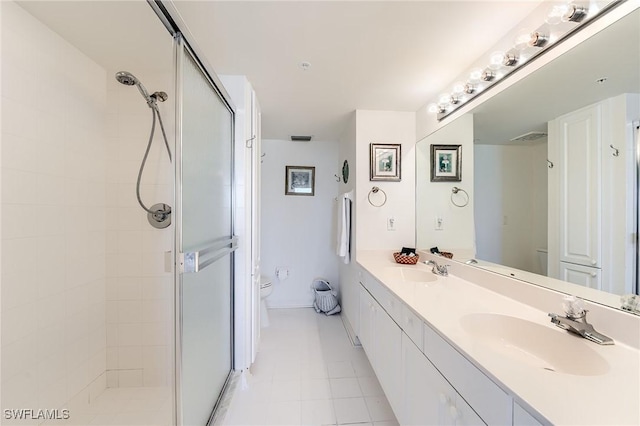 bathroom with tile patterned flooring, vanity, a shower with shower door, and toilet