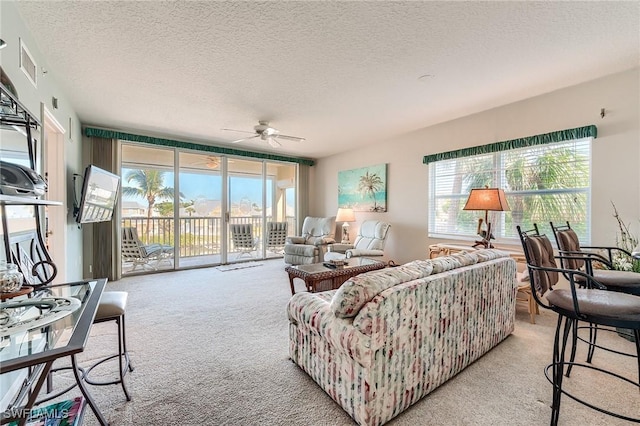 carpeted living room featuring a textured ceiling, plenty of natural light, and ceiling fan