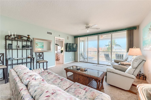 carpeted living room featuring ceiling fan and a textured ceiling