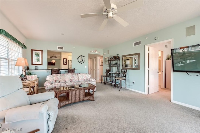 living room with a textured ceiling, ceiling fan, and light carpet