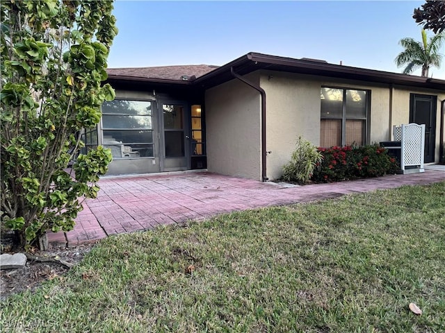 back of property with a lawn and a patio