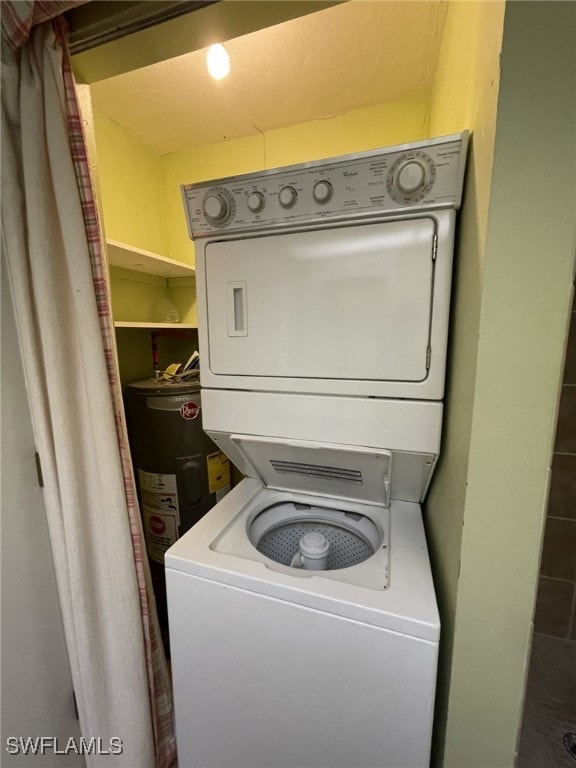 clothes washing area featuring stacked washer / drying machine and water heater