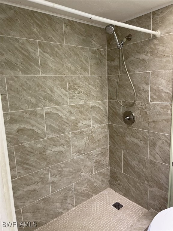 bathroom with a tile shower and toilet