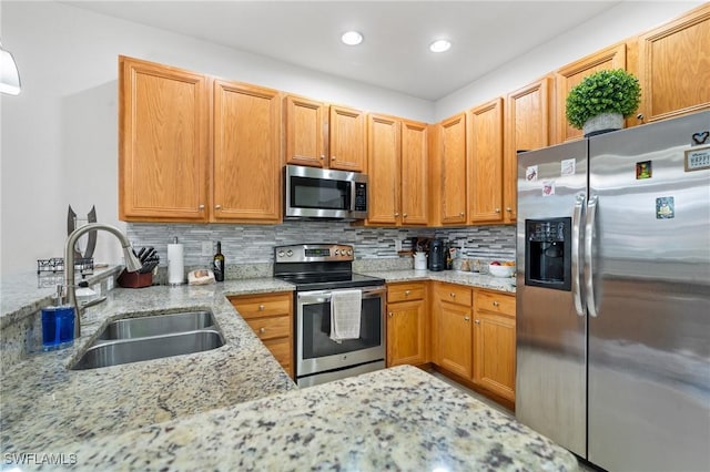 kitchen with sink, appliances with stainless steel finishes, tasteful backsplash, light stone counters, and kitchen peninsula