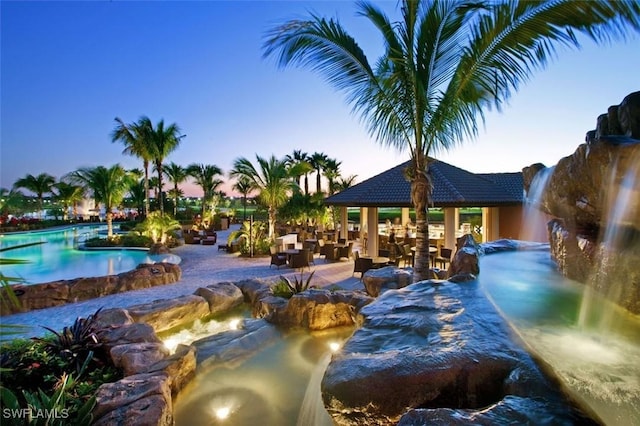 pool at dusk featuring a gazebo