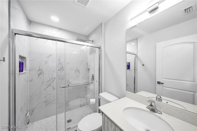 bathroom with a shower with door, vanity, and toilet