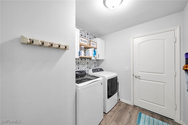 washroom with cabinets, light wood-type flooring, and washing machine and clothes dryer