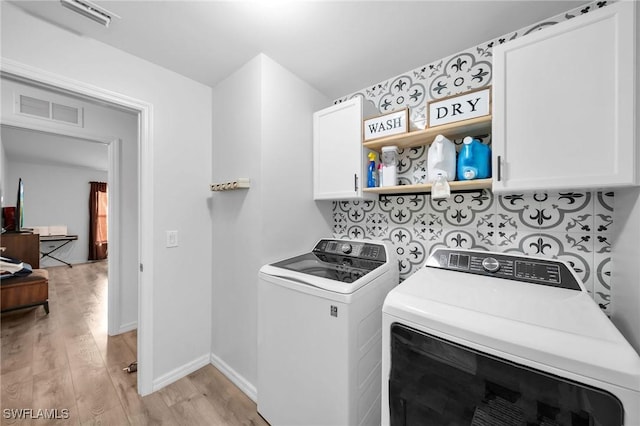 clothes washing area with light hardwood / wood-style floors, cabinets, and washing machine and dryer