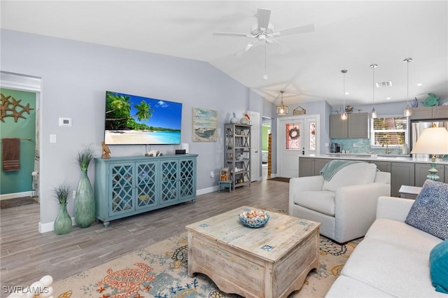 living room with ceiling fan, light hardwood / wood-style floors, and lofted ceiling