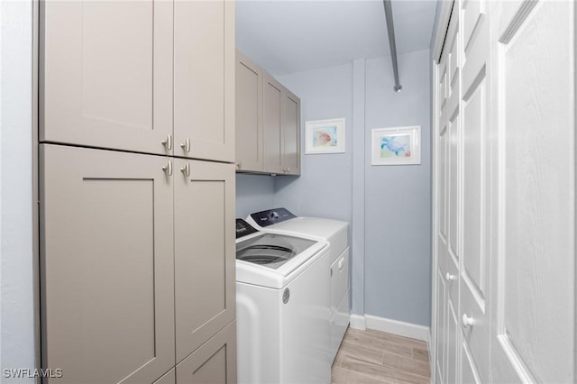 clothes washing area featuring washer and clothes dryer, cabinets, and light hardwood / wood-style flooring