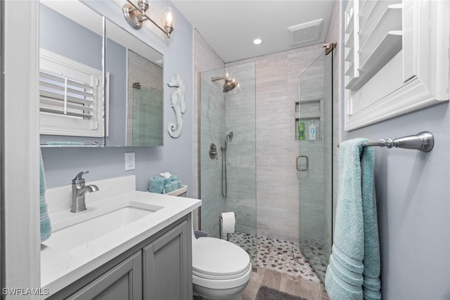 bathroom featuring vanity, toilet, and a shower with shower door