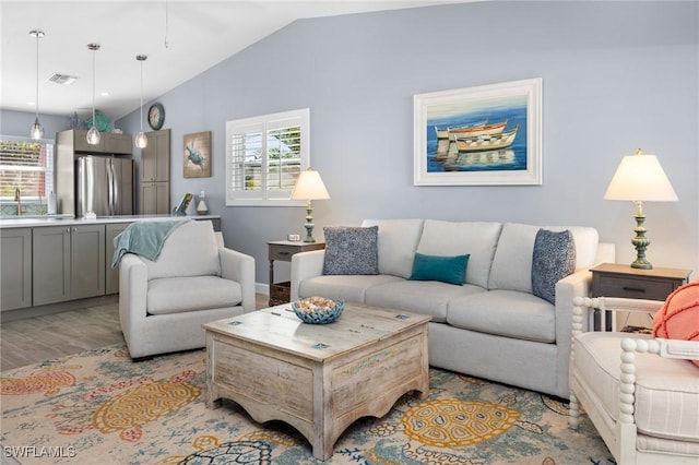 living room with light hardwood / wood-style floors, vaulted ceiling, and sink