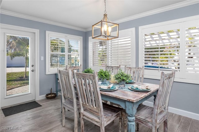 dining area featuring a notable chandelier, a healthy amount of sunlight, ornamental molding, and light hardwood / wood-style flooring