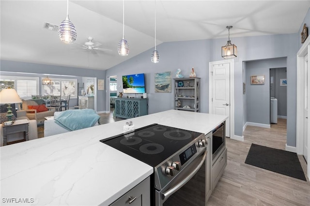 kitchen featuring vaulted ceiling, light wood-type flooring, decorative light fixtures, and appliances with stainless steel finishes