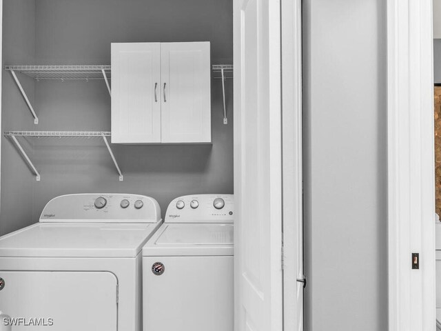 clothes washing area featuring cabinets and independent washer and dryer