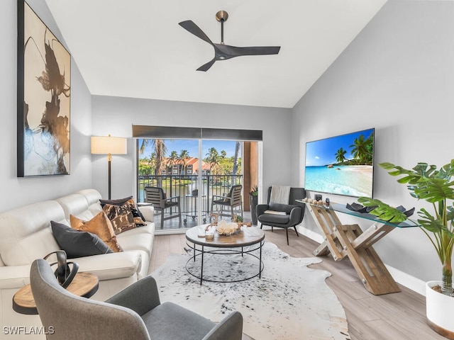 living room with ceiling fan, light hardwood / wood-style floors, and vaulted ceiling