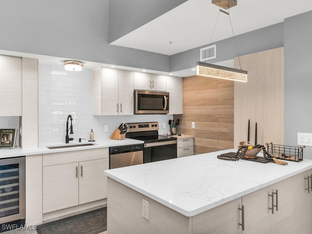 kitchen featuring sink, beverage cooler, stainless steel appliances, tasteful backsplash, and light stone counters