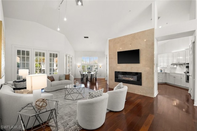 living area with high vaulted ceiling, a large fireplace, visible vents, and dark wood finished floors