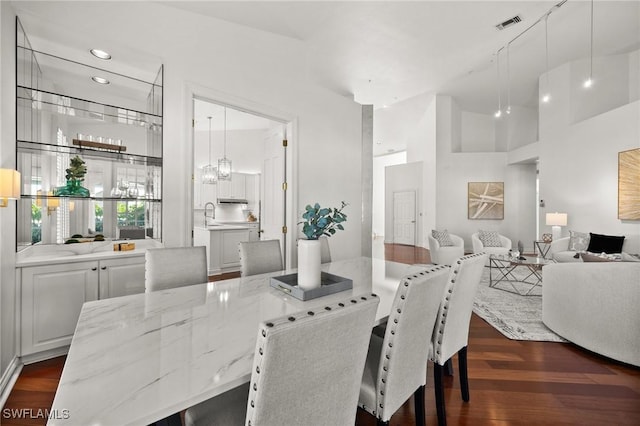 dining room with visible vents, dark wood finished floors, and a high ceiling