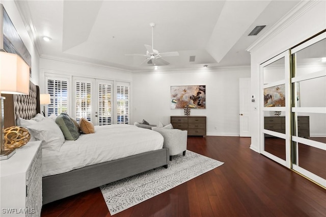 bedroom featuring dark hardwood / wood-style floors, a tray ceiling, and crown molding