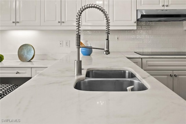 kitchen with white cabinetry, sink, backsplash, light stone counters, and black electric cooktop