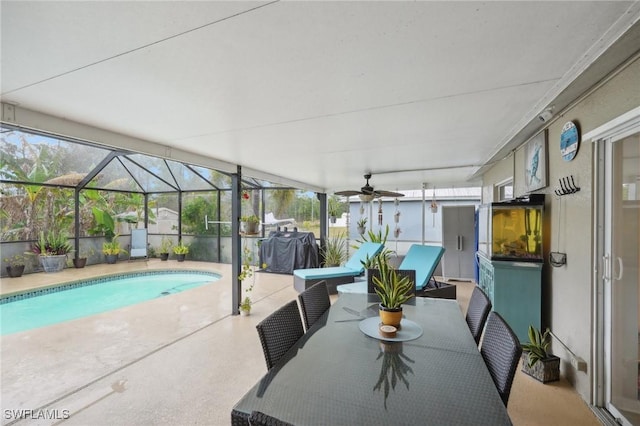 exterior space featuring ceiling fan, area for grilling, a patio area, and glass enclosure