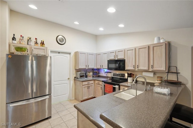 kitchen with kitchen peninsula, appliances with stainless steel finishes, light brown cabinetry, lofted ceiling, and light tile patterned flooring