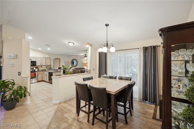 dining space featuring ceiling fan with notable chandelier, vaulted ceiling, and light wood-type flooring