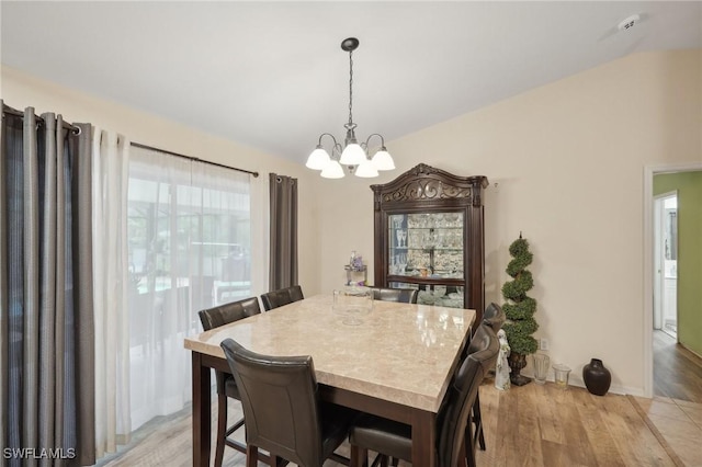 dining space with light hardwood / wood-style floors and an inviting chandelier