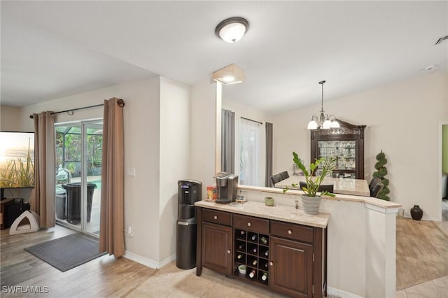 kitchen featuring dark brown cabinets, an inviting chandelier, light hardwood / wood-style flooring, and decorative light fixtures