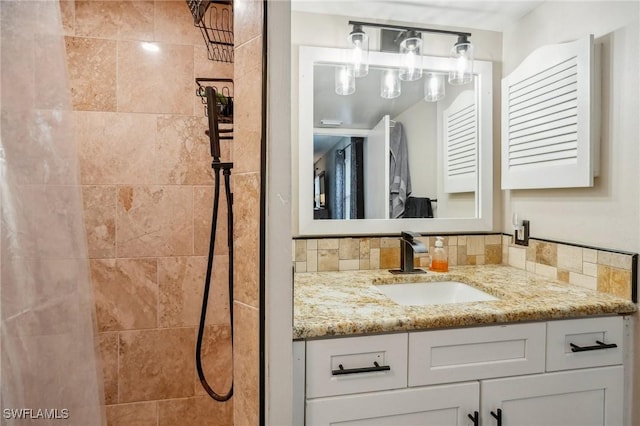 bathroom with a tile shower, tasteful backsplash, and vanity