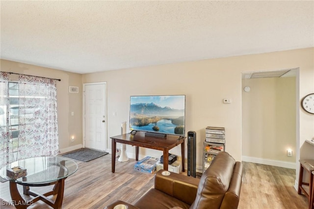 living room featuring a textured ceiling and light wood-type flooring