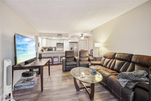 living room featuring ceiling fan, hardwood / wood-style floors, and a textured ceiling